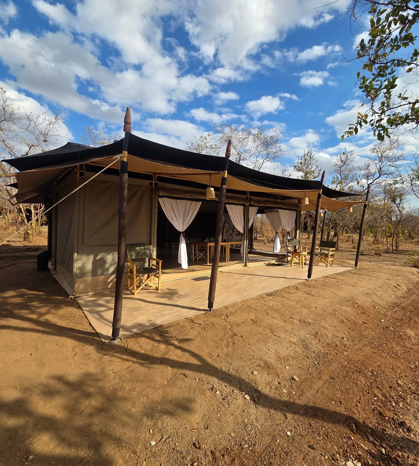 The open-sided mess tent at Kijani Camp under a blue sky, with its shaded veranda